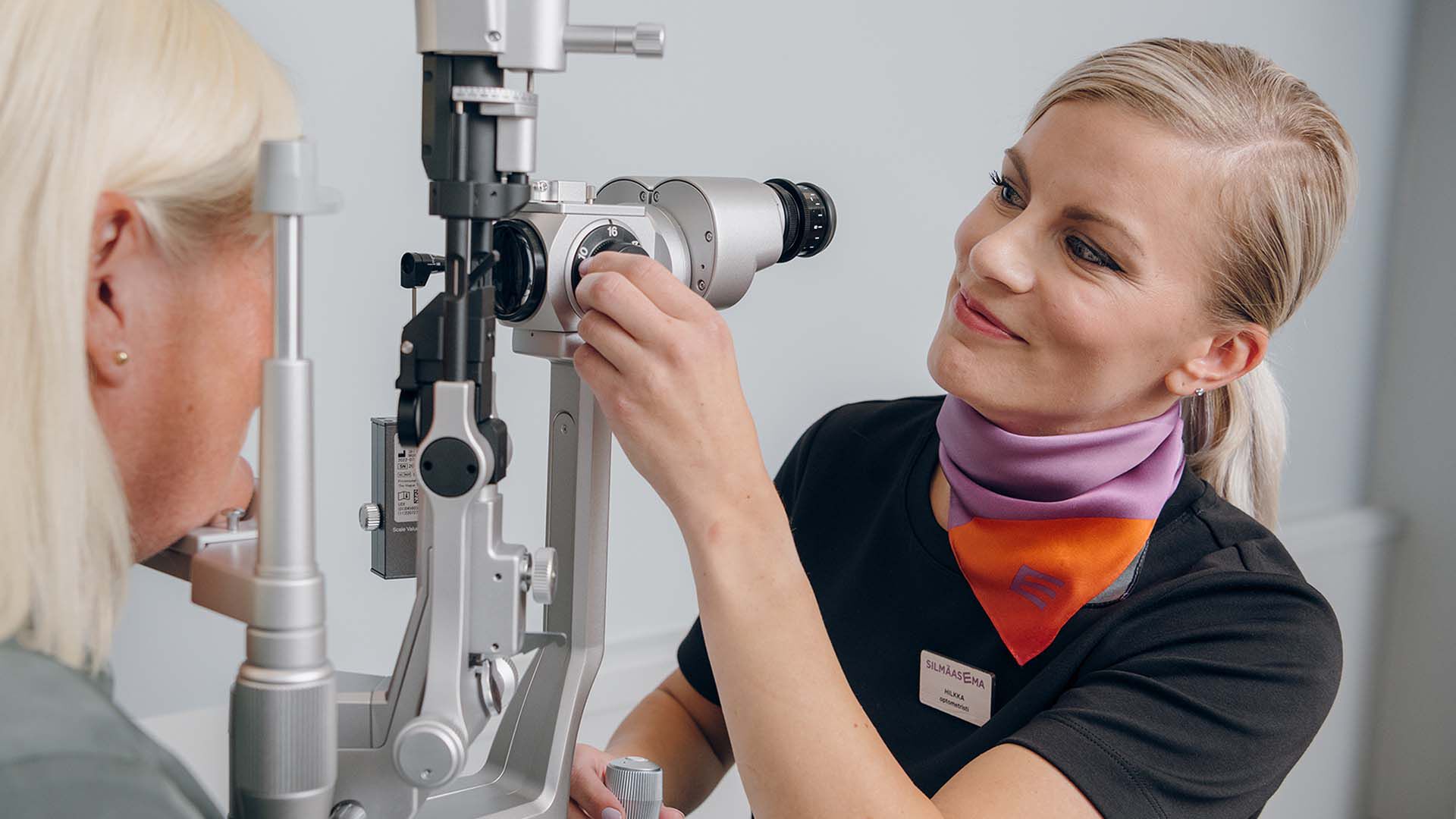 Optician carrying out an eye examination with a customer in an examination room.